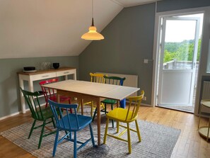 A dining area with a table, chairs, a hanging light fixture, a window with a view, and a radiator. - 4 Person Holiday Home in Nosund (Nosund)
