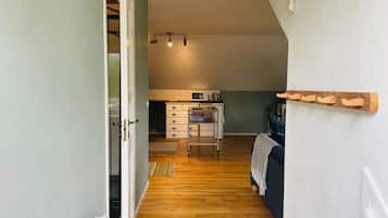 A narrow hallway leading to a kitchen with a microwave and a small table.