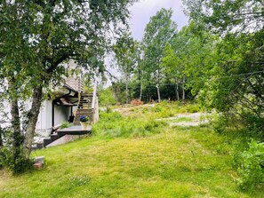 A wooden staircase leading to a building surrounded by lush greenery and trees. - 4 Person Holiday Home in Nosund (Nosund)