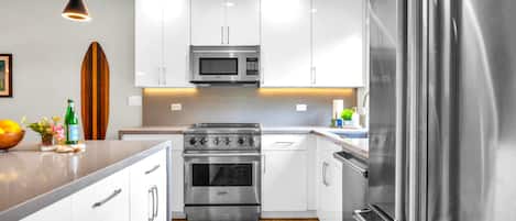 Una cocina moderna con armarios blancos, electrodomésticos de acero inoxidable y encimera de madera.
