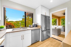 Una cocina moderna con un ventanal grande, electrodomésticos de acero inoxidable y vistas a un jardín exuberante.