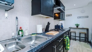 Una cocina moderna con dos fregaderos, una estufa y un pequeño comedor con taburetes.