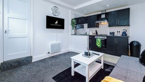 Una cocina moderna con gabinetes negros, encimera blanca y hervidor negro.