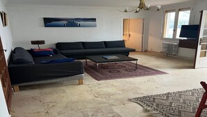 Un salon avec un canapé noir, une table basse et un tapis à motifs.