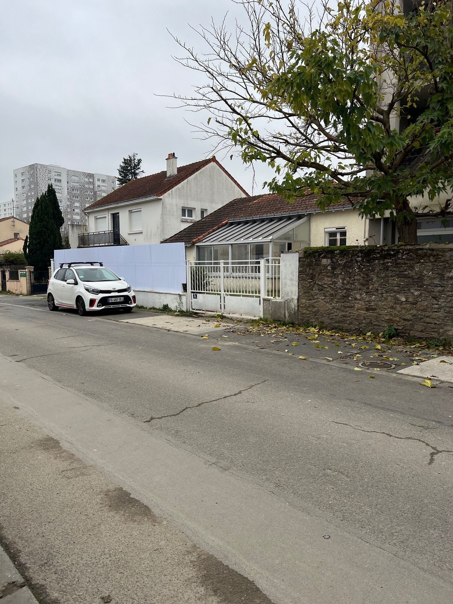 Een woonstraat met huizen, een geparkeerde auto en een boom.