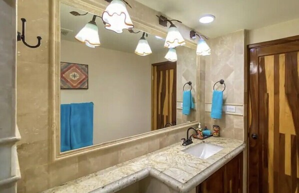 A bathroom with a large mirror, a sink, and a wooden door.