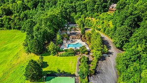 Une vue aérienne d’une maison avec une piscine, entourée d’une végétation luxuriante et d’une pelouse bien entretenue.