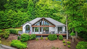 Une maison moderne à deux étages, dotée d’une grande terrasse et entourée d’arbres verdoyants et luxuriants.