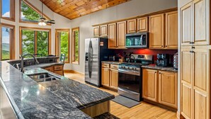 Une cuisine moderne avec des meubles en bois, des appareils électroménagers en acier inoxydable et de grandes fenêtres.