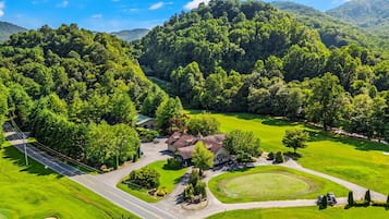 A residential area with a house surrounded by lush greenery and a golf course.
