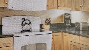 A kitchen with wooden cabinets, a stainless steel range, and a coffee maker on the countertop.