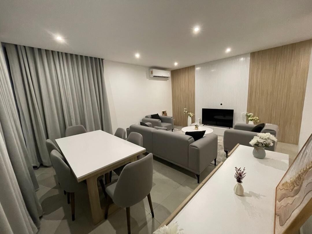 Una sala de estar moderna con un sofá, una mesa de comedor y una televisión.