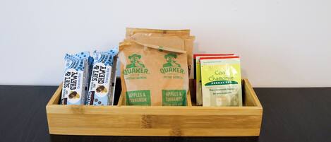 A wooden box containing instant oatmeal packets, Quaker brand, and a box of Chomolilly tea.