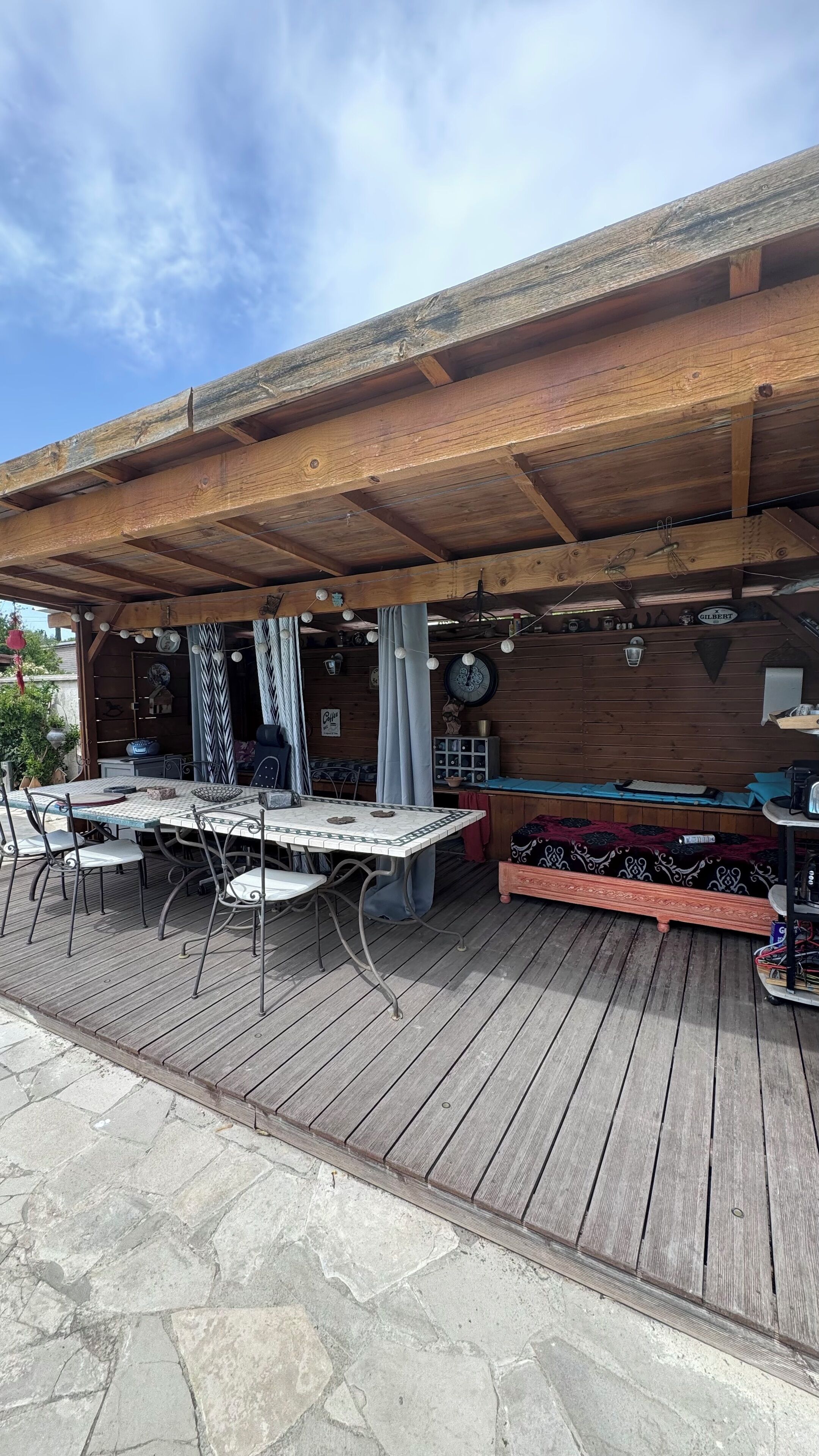 Une terrasse extérieure avec une plateforme en bois, un espace salon couvert et une table avec des chaises.