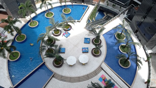 Una piscina de varios niveles con palmeras y zonas de descanso.