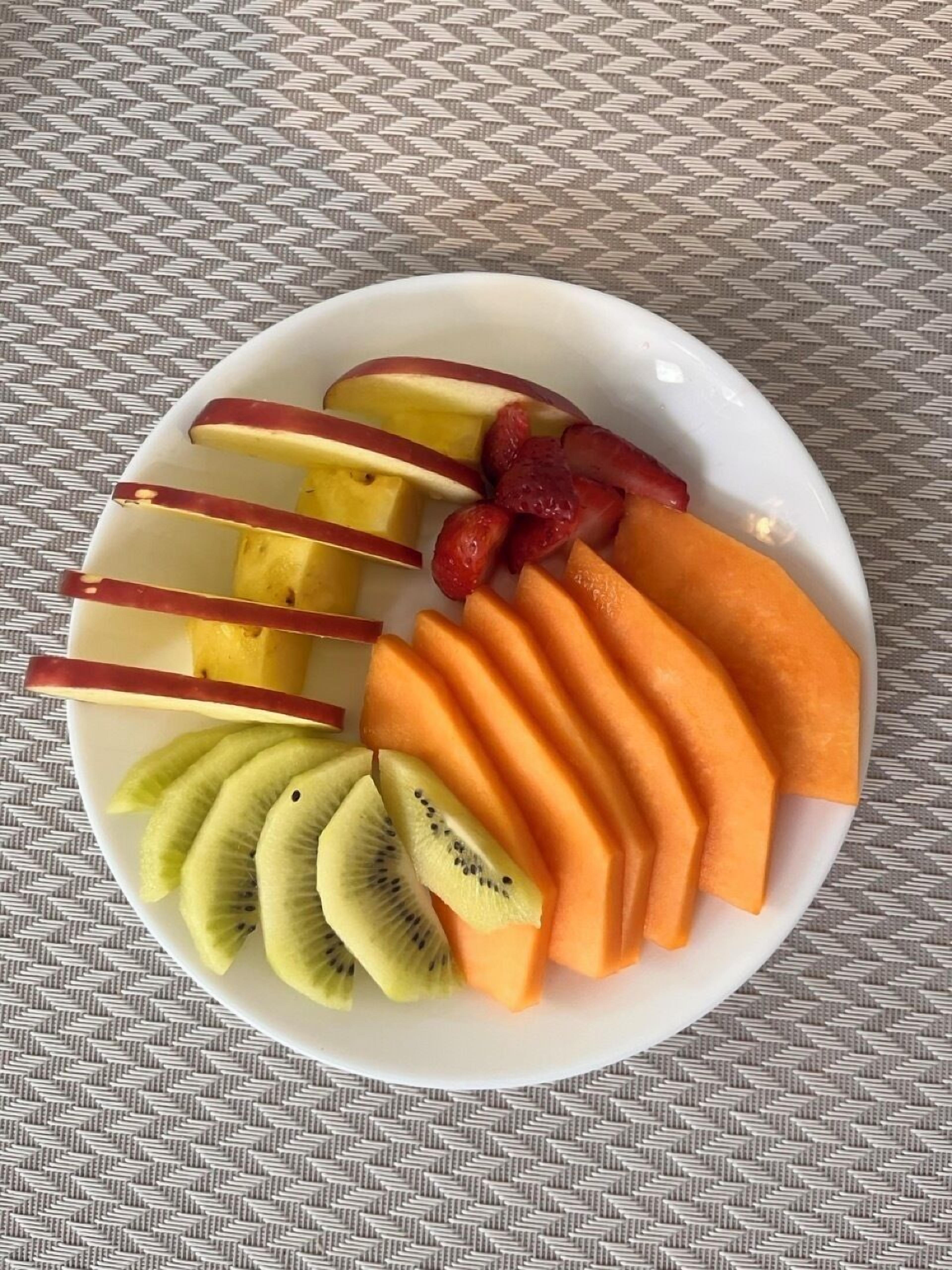 A white plate with sliced fruits on a textured surface.