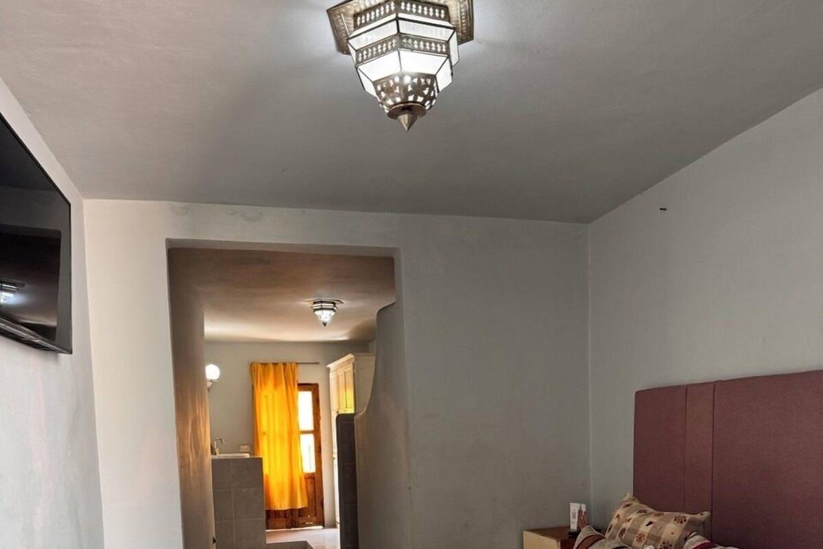 Ein Hotelzimmer mit einem großen Bett, einem Flachbildfernseher, einer Kristallleuchtre und einem durchgehenden Türbogen einsehbaren Badezimmer.