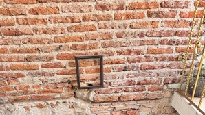 Un mur de briques avec trois encadrements carrés et un escalier aux marches vertes et aux rampes métalliques.