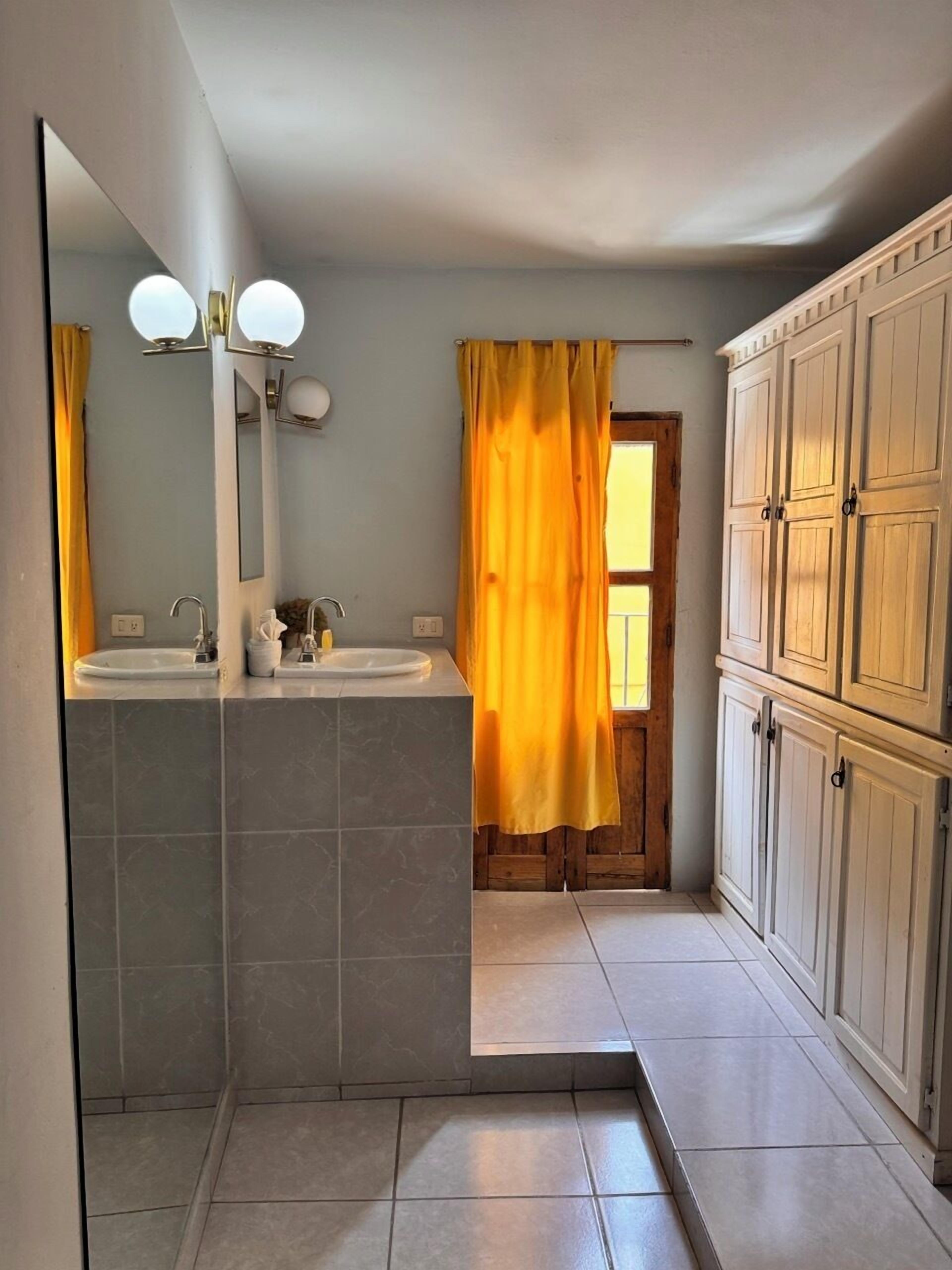 A bathroom with two sinks, a mirror, and a shower curtain.