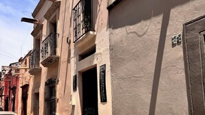 Une rue étroite avec un trottoir pavé de pierres, une voiture garée et un bâtiment sur lequel on peut lire une enseigne indiquant un hôtel appelé « Hotel Casa 22 ».