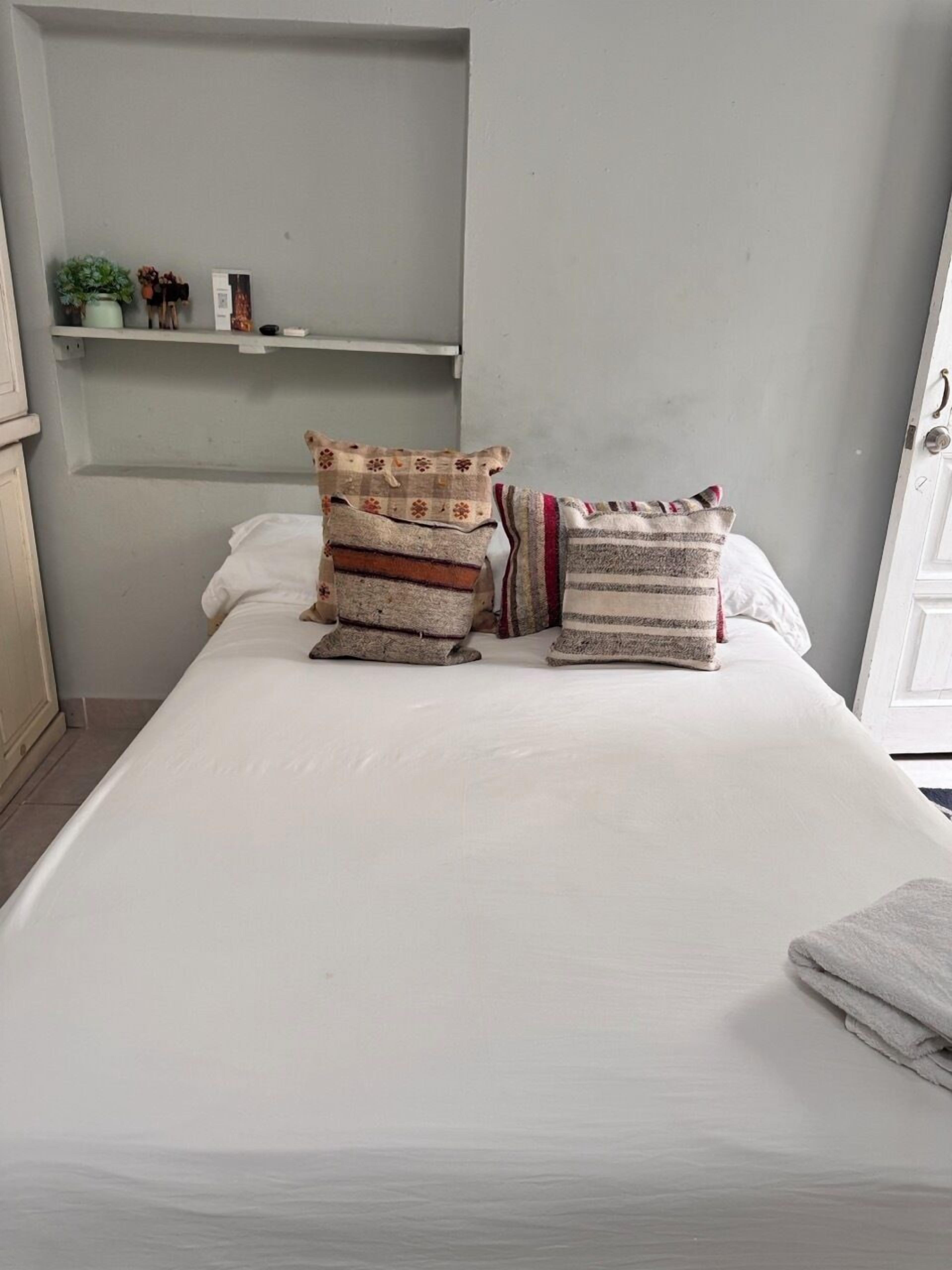 Un letto rifatto con diversi cuscini e una coperta piegata.