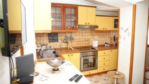 Una cuina petita amb armaris grocs, fogó i un rentaplat.