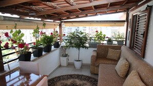 Un balcó amb un sofà, cadires i plantes en testos.