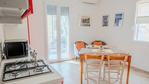 Een moderne keuken met een gasfornuis, een magnetron en een eethoek met een tafel en stoelen.