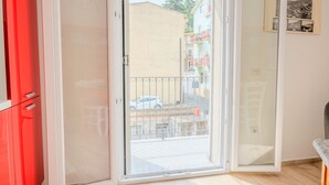 Een kamer met een schuifdeur naar een balkon, een rode kast en een ingelijste foto aan de muur.