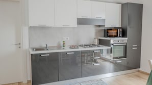 A modern kitchen with stainless steel appliances, white cabinets, and a grey countertop.