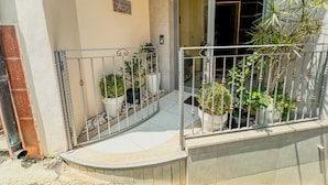 A balcony with potted plants, a metal railing, and a door leading to an interior space. - B&B by Family L&G - Vibo Marina (Vibo Marina)