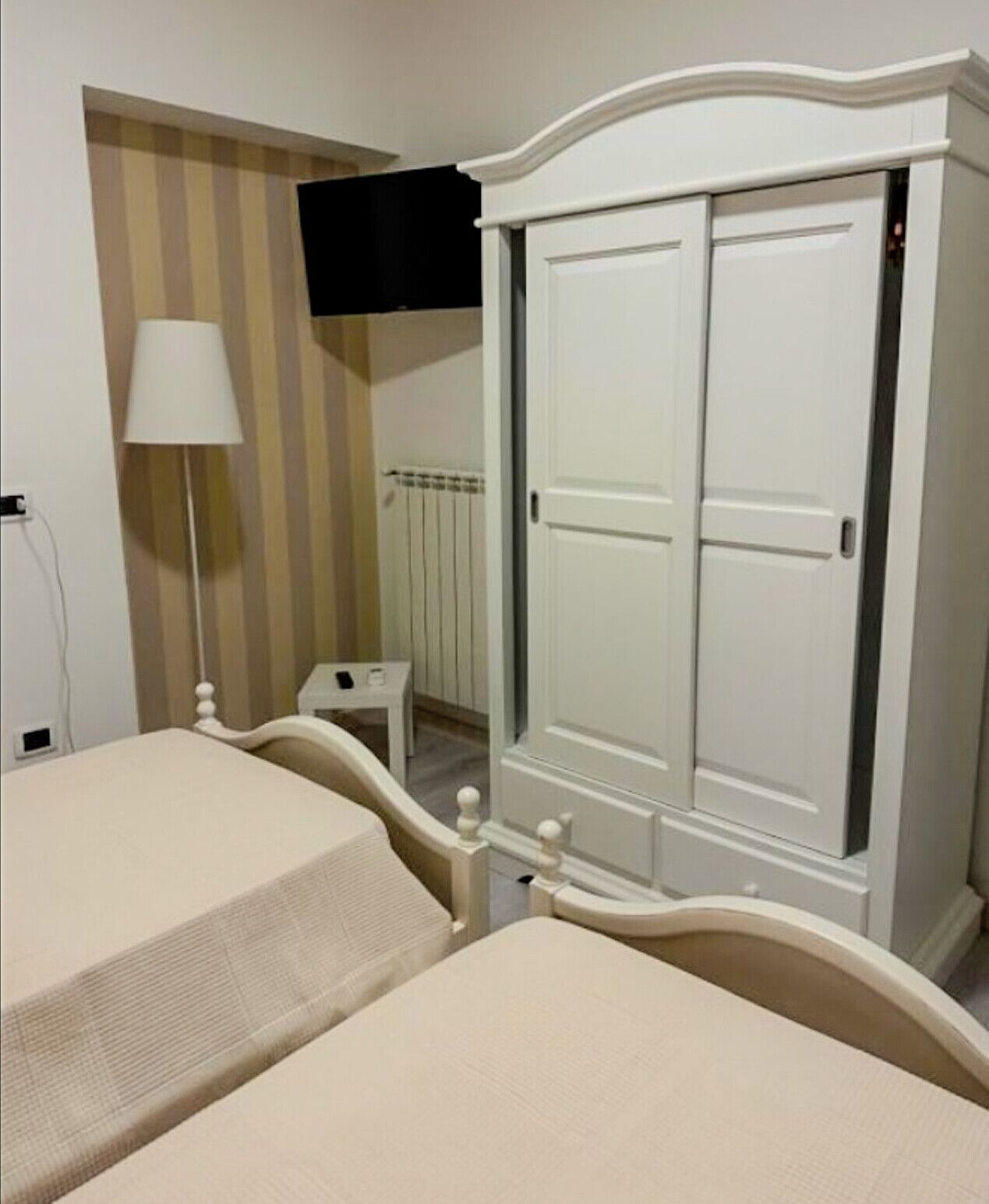 A bedroom with a bed, a wardrobe, a lamp, and a radiator.