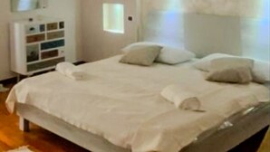 A bedroom with a bed, pillows, a bedside table, a mirror, and a wall-mounted artwork. - B&B by Family L&G - Vibo Marina (Vibo Marina)