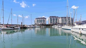 A marina with multiple boats docked, a clear sky, and buildings in the background. - On the Water 7 Free Parking By My Getaways (Brighton)