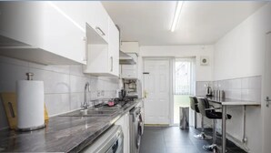 A modern kitchen with white cabinets, a marble countertop, and stainless steel appliances. - Fully kitted, 4BR w/Parking, private Garden, Wi-Fi,Near City, Stadiums & Airport (Manchester)