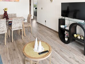 Una sala de estar moderna con televisor, una mesa redonda con adornos y un árbol de Navidad.