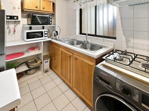Una cocina compacta con microondas, estufa, lavamanos y armarios.