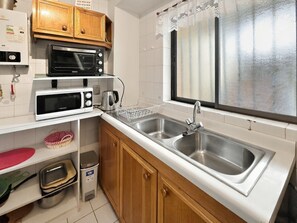 A compact kitchen with a double sink, a microwave, a toaster, and a kettle. - Oceana Suites Ensenada Villarrica (Villarrica)
