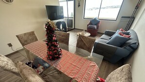 A modern living space with a dining table, chairs, a Christmas tree, a sofa, and a TV. - Oceana Suites Ensenada Villarrica (Villarrica)