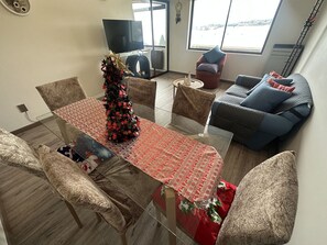 A modern living space with a dining table, chairs, a Christmas tree, a sofa, and a TV.