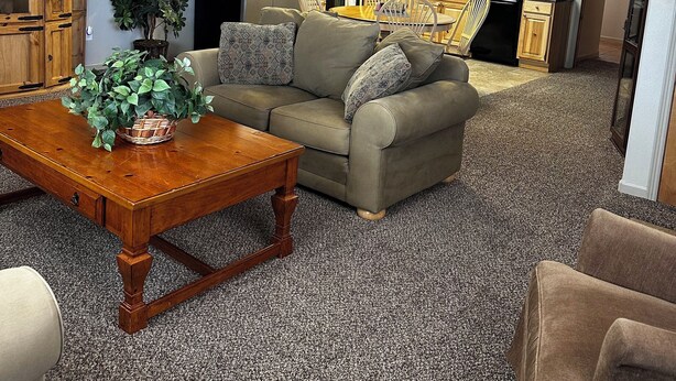 A spacious living room with a wooden coffee table, a sofa, and a ceiling fan.