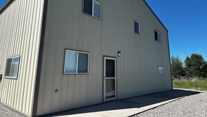 A large, single-story industrial building with a flat roof and a door leading to an interior space.