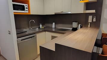 Cocina moderna equipada con microondas, lavamanos y cafetera.