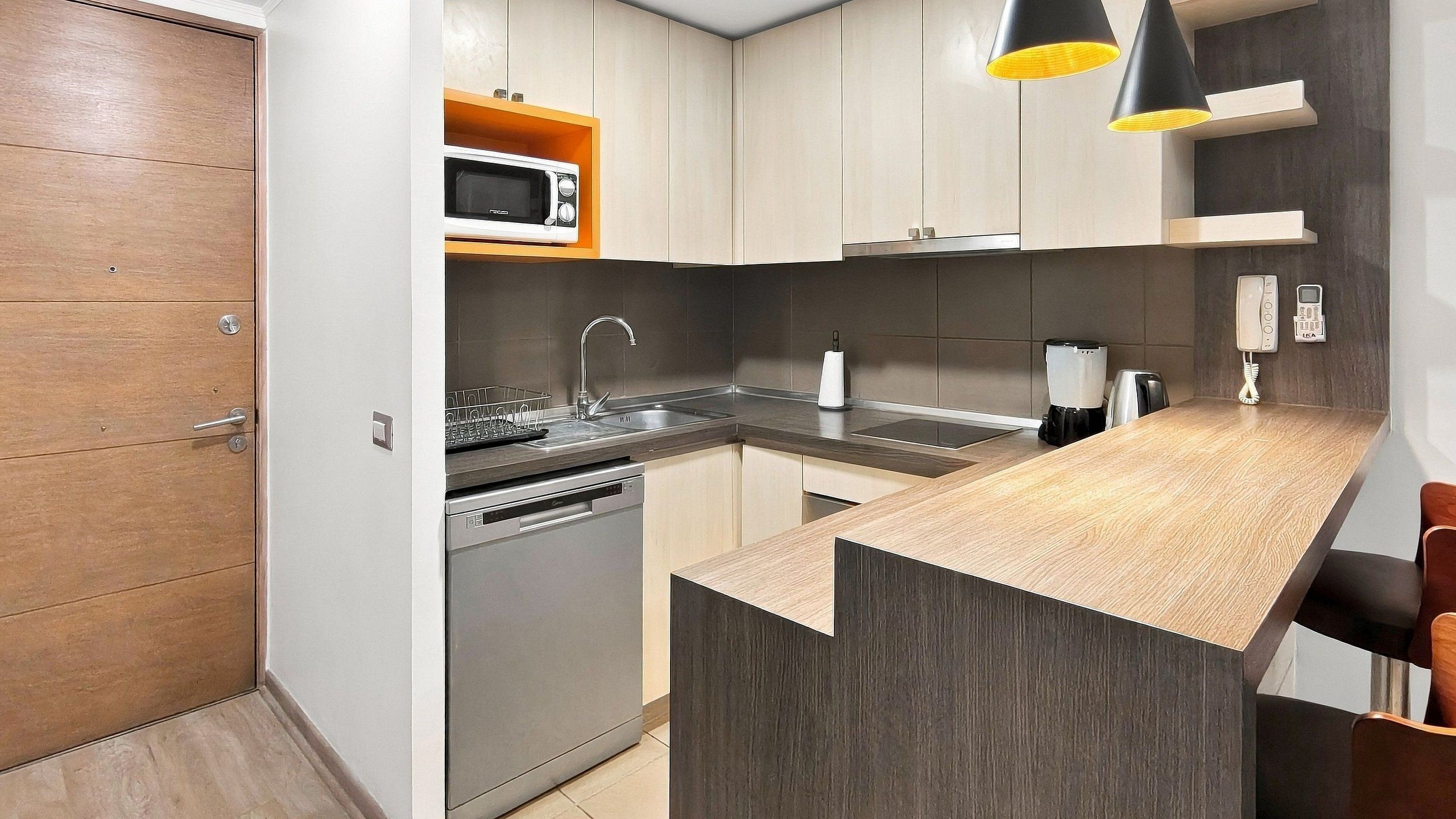 Una cocina moderna con horno empotrado, microondas, fregadero y cafetera.