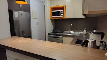 Una cocina moderna con microondas integrado, electrodomésticos de acero inoxidable y encimera de madera.