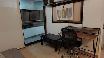 Un pequeño espacio de oficina con un escritorio, una silla y un ventanal grande.