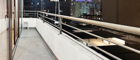 A balcony with a metal railing, a small table, and chairs.