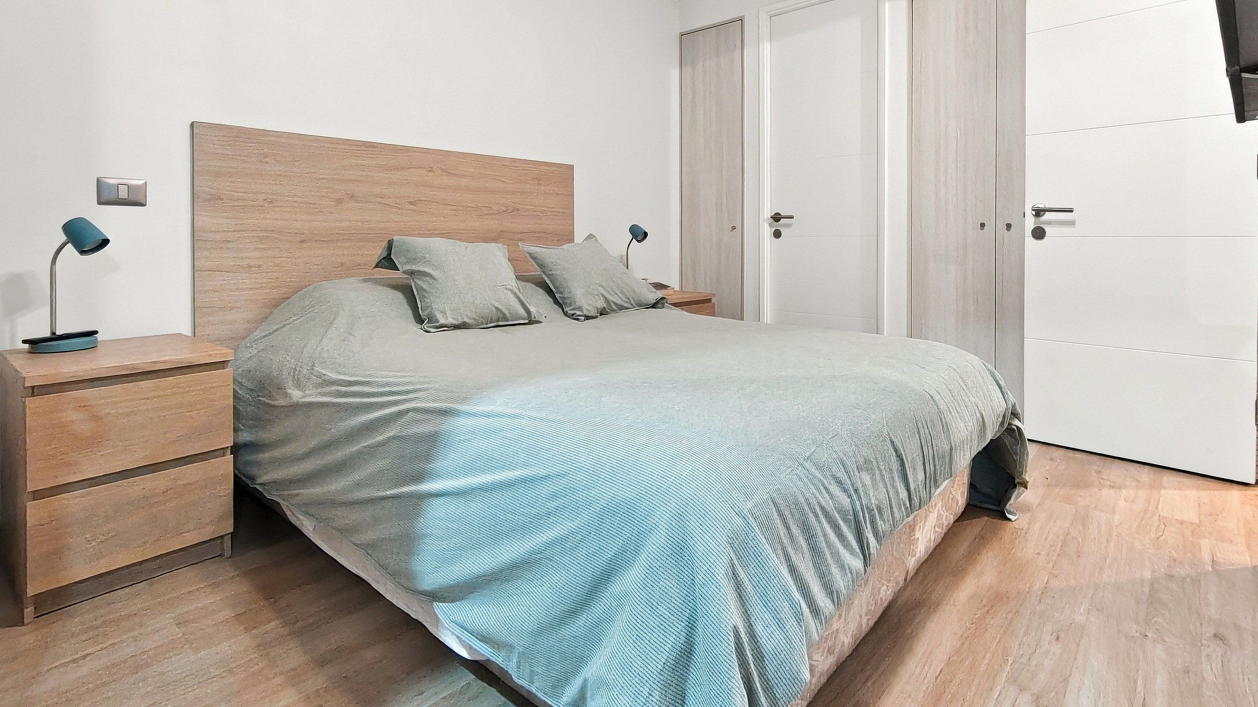 Une chambre à coucher comprenant un lit, deux tables de chevet, une commode et une armoire.