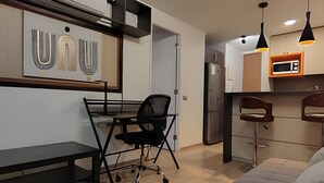 Een moderne woonruimte met een bureau, een bank, een keuken en een eettafel.