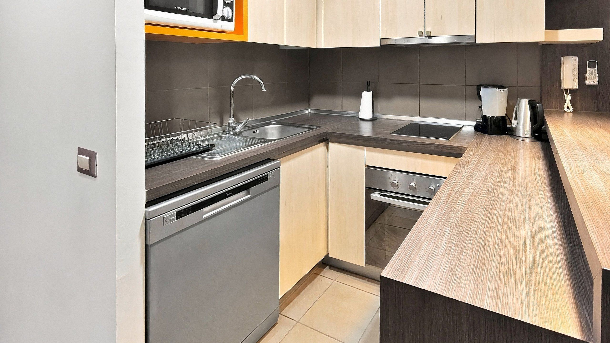 A modern kitchen with stainless steel appliances, a dishwasher, an oven, and a sink.